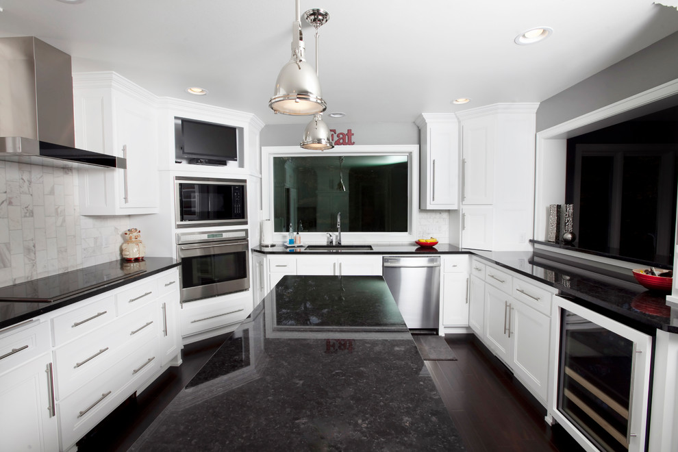Example of a minimalist u-shaped dark wood floor enclosed kitchen design in Other with an undermount sink, recessed-panel cabinets, white cabinets, granite countertops, white backsplash, subway tile backsplash, stainless steel appliances and an island