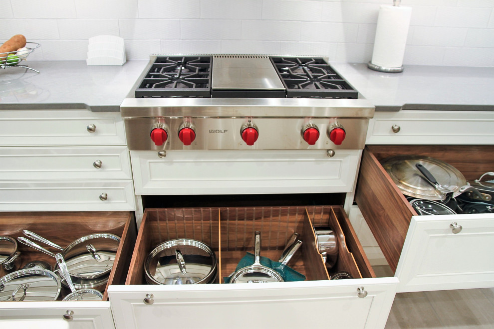 Bild på ett stort vintage flerfärgad flerfärgat kök, med luckor med infälld panel, vita skåp, bänkskiva i kvarts, vitt stänkskydd, stänkskydd i tunnelbanekakel, rostfria vitvaror, en undermonterad diskho, klinkergolv i porslin, en köksö och beiget golv