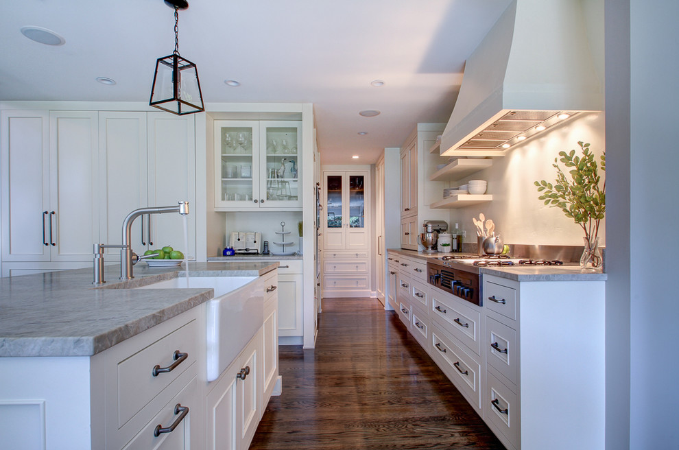 Mittelgroße Moderne Küche mit Landhausspüle, flächenbündigen Schrankfronten, weißen Schränken, Quarzit-Arbeitsplatte, braunem Holzboden und Kücheninsel in Chicago