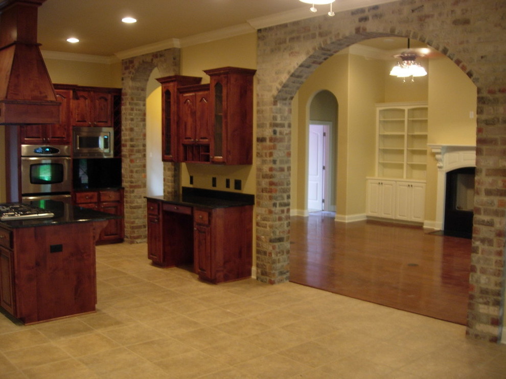 Inredning av ett amerikanskt mellanstort kök, med luckor med upphöjd panel, skåp i mörkt trä, bänkskiva i koppar, travertin golv, en köksö och beiget golv