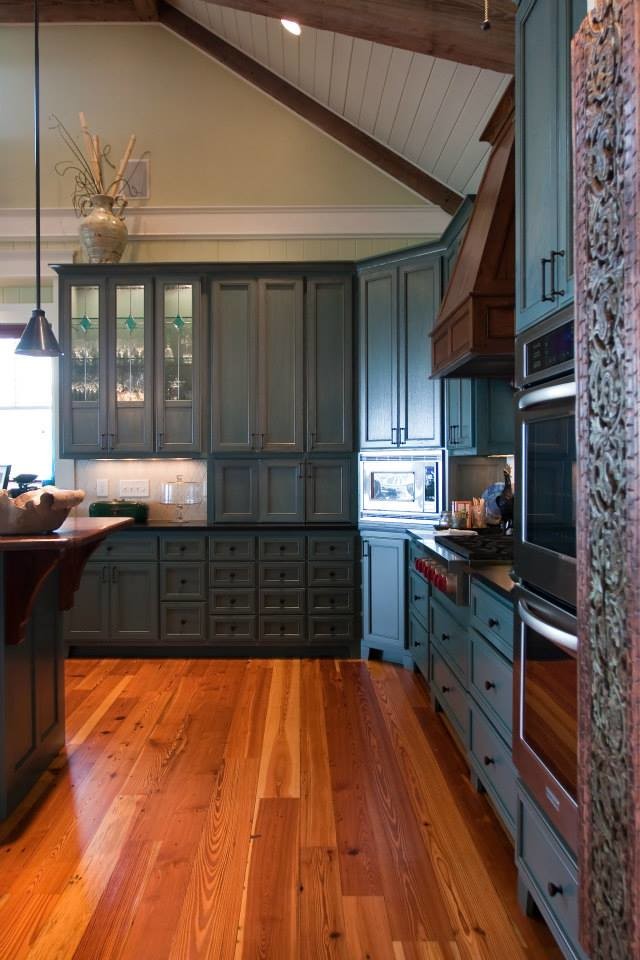Bild på ett stort lantligt kök, med blå skåp, bänkskiva i onyx, vitt stänkskydd, stänkskydd i porslinskakel, rostfria vitvaror, en köksö, skåp i shakerstil, mellanmörkt trägolv och brunt golv
