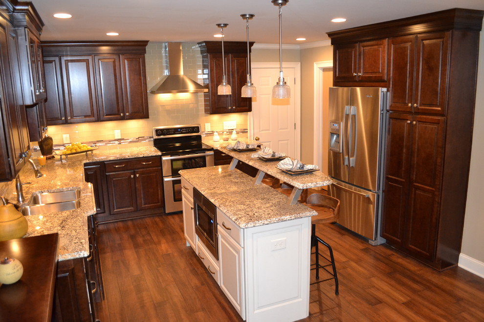 Example of a mid-sized transitional l-shaped medium tone wood floor open concept kitchen design in Other with an undermount sink, raised-panel cabinets, dark wood cabinets, marble countertops, beige backsplash, subway tile backsplash, stainless steel appliances and an island