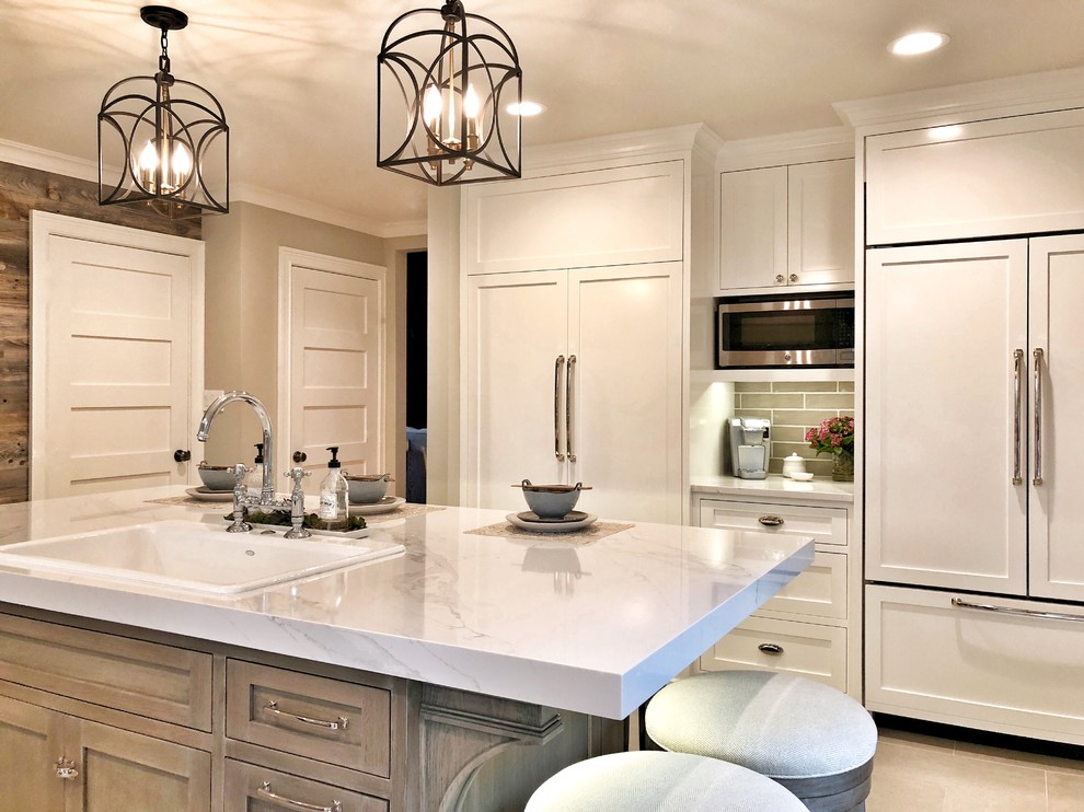 Example of a large country galley limestone floor and gray floor kitchen pantry design in Other with a drop-in sink, shaker cabinets, white cabinets, quartz countertops, beige backsplash, ceramic backsplash, stainless steel appliances, an island and white countertops