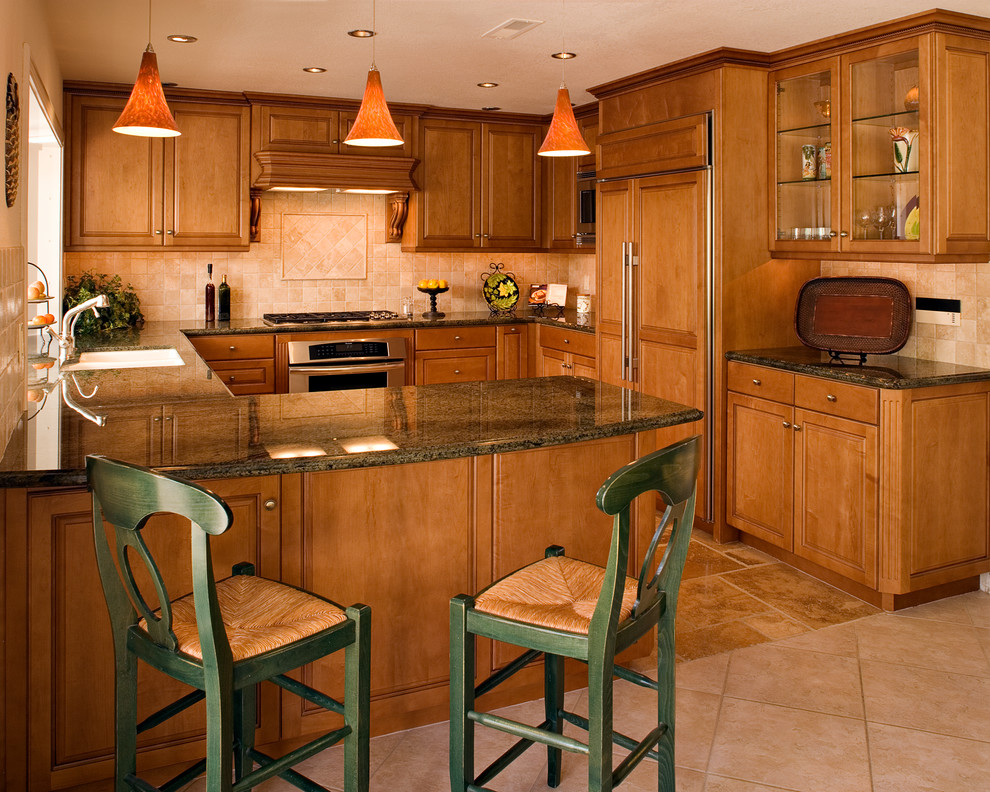 Klassisk inredning av ett mellanstort kök, med en undermonterad diskho, luckor med upphöjd panel, skåp i ljust trä, granitbänkskiva, beige stänkskydd, stänkskydd i stenkakel, rostfria vitvaror, travertin golv och en halv köksö
