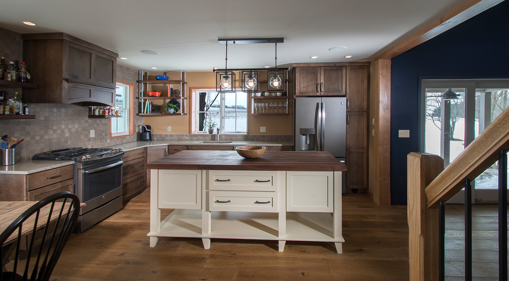 Rustic kitchen/diner in New York with a built-in sink, recessed-panel cabinets, white cabinets, engineered stone countertops, ceramic splashback, stainless steel appliances, medium hardwood flooring, an island, brown floors and multi-coloured splashback.