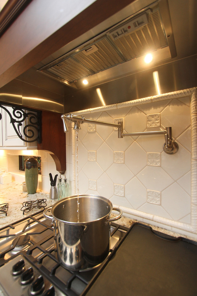 Idéer för ett medelhavsstil kök, med en undermonterad diskho, luckor med upphöjd panel, granitbänkskiva, vitt stänkskydd, glaspanel som stänkskydd och rostfria vitvaror