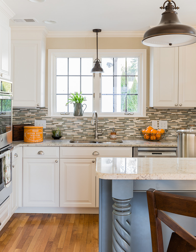 Mid-sized elegant l-shaped medium tone wood floor and brown floor enclosed kitchen photo in Boston with an island, an undermount sink, raised-panel cabinets, white cabinets, quartz countertops, multicolored backsplash, matchstick tile backsplash and stainless steel appliances
