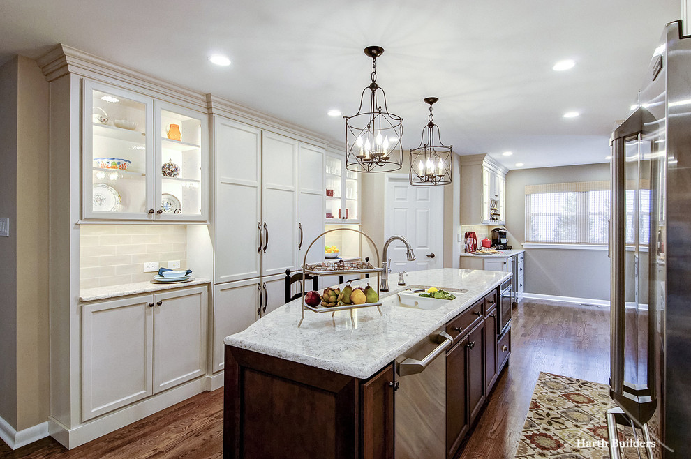 Eat-in kitchen - mid-sized transitional galley medium tone wood floor eat-in kitchen idea in Philadelphia with an undermount sink, recessed-panel cabinets, white cabinets, quartz countertops, beige backsplash, glass tile backsplash, stainless steel appliances and an island
