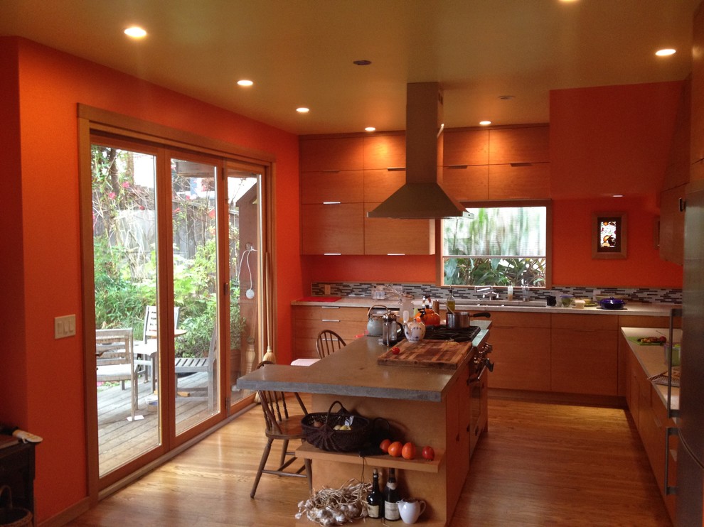 This is an example of a large contemporary l-shaped open plan kitchen in San Diego with a submerged sink, flat-panel cabinets, medium wood cabinets, concrete worktops, multi-coloured splashback, matchstick tiled splashback, stainless steel appliances, light hardwood flooring, an island and beige floors.