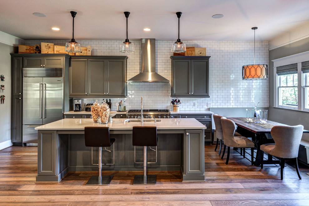 Large transitional galley medium tone wood floor open concept kitchen photo in Atlanta with an undermount sink, recessed-panel cabinets, gray cabinets, quartz countertops, white backsplash, subway tile backsplash, stainless steel appliances and an island