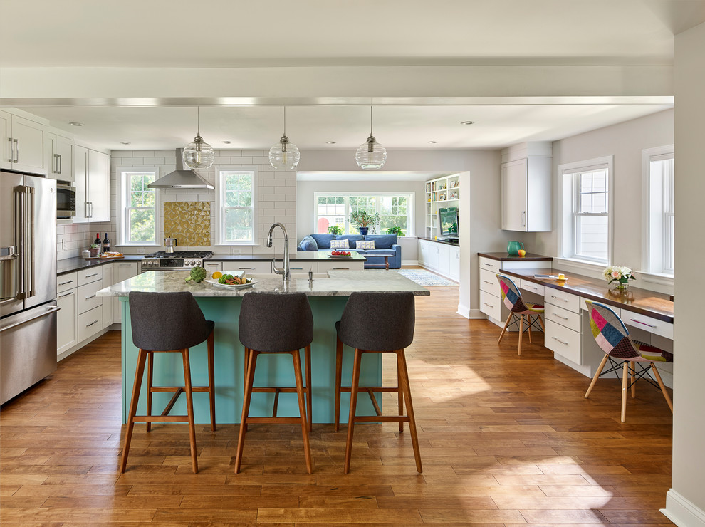 Inspiration for a mid-sized contemporary l-shaped medium tone wood floor open concept kitchen remodel in Philadelphia with a farmhouse sink, shaker cabinets, turquoise cabinets, quartz countertops, white backsplash, subway tile backsplash, stainless steel appliances, an island and gray countertops