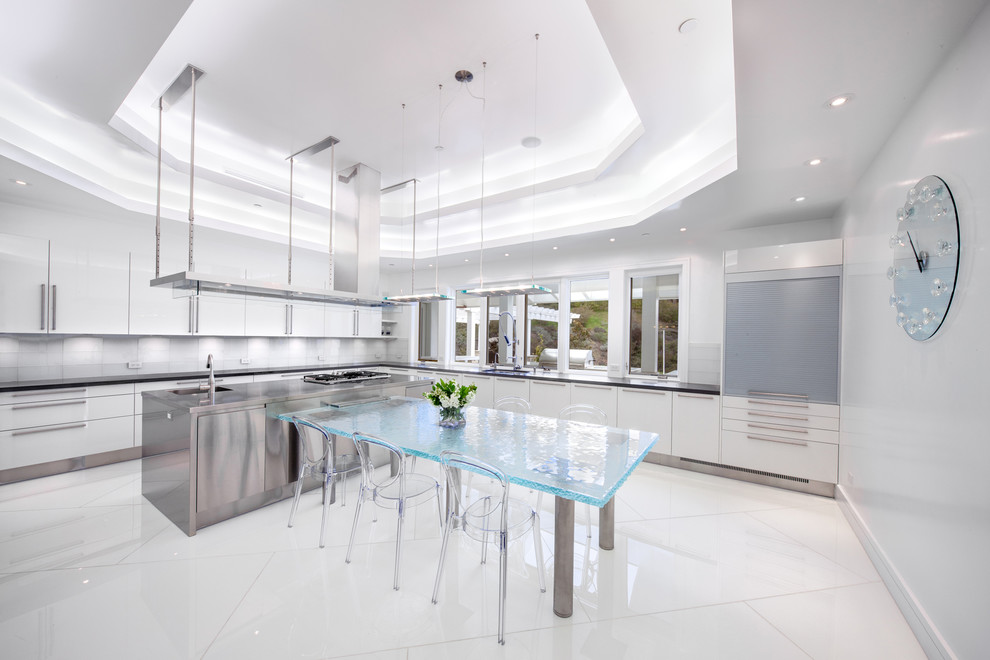 This is an example of a large contemporary l-shaped kitchen/diner in Los Angeles with an integrated sink, flat-panel cabinets, white cabinets, stainless steel worktops, white splashback and an island.