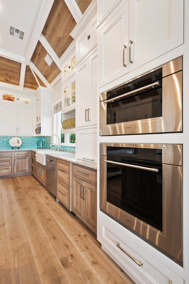 Exempel på ett stort exotiskt beige beige kök, med en undermonterad diskho, luckor med profilerade fronter, vita skåp, bänkskiva i kvartsit, blått stänkskydd, stänkskydd i glaskakel, rostfria vitvaror, ljust trägolv, flera köksöar och brunt golv