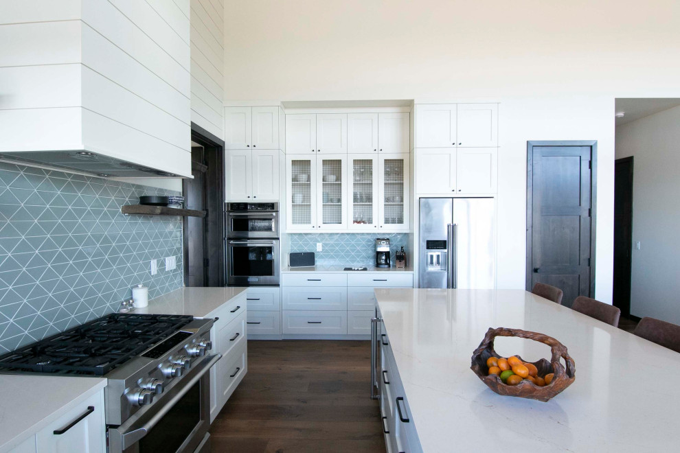 Foto di una grande cucina stile marinaro con ante bianche, paraspruzzi grigio, paraspruzzi con piastrelle in ceramica, elettrodomestici in acciaio inossidabile, parquet scuro, pavimento marrone e top bianco