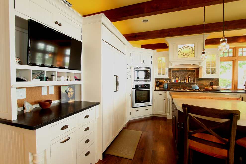 Inspiration för stora lantliga kök, med en trippel diskho, luckor med profilerade fronter, vita skåp, granitbänkskiva, flerfärgad stänkskydd, stänkskydd i stenkakel, integrerade vitvaror, en köksö och mellanmörkt trägolv