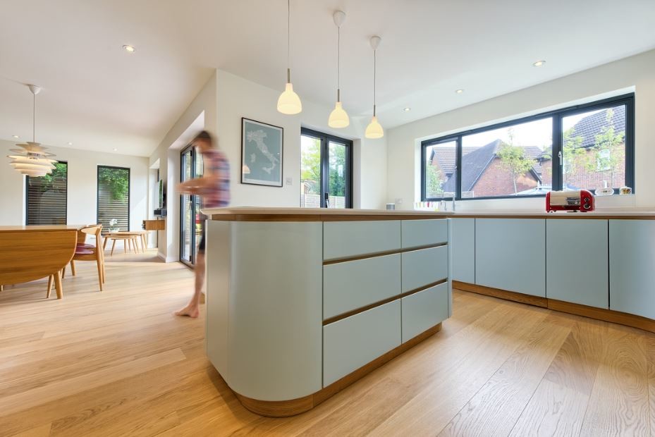 Medium sized scandi open plan kitchen in Hertfordshire with flat-panel cabinets, blue cabinets, granite worktops, light hardwood flooring and an island.
