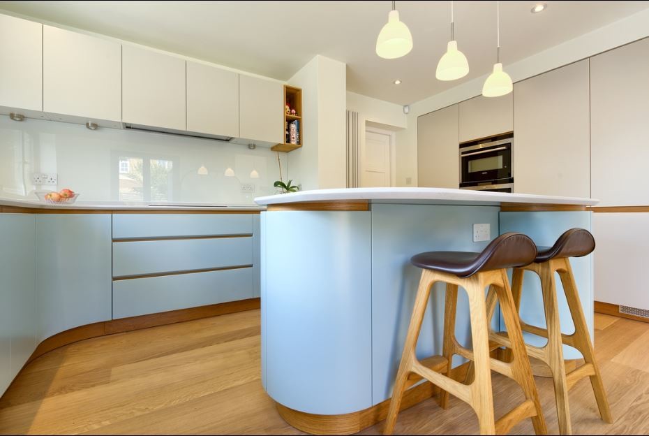 Minimalistisk inredning av ett mellanstort linjärt kök med öppen planlösning, med släta luckor, blå skåp, granitbänkskiva, vitt stänkskydd, stänkskydd i glaskakel, svarta vitvaror, ljust trägolv och en köksö