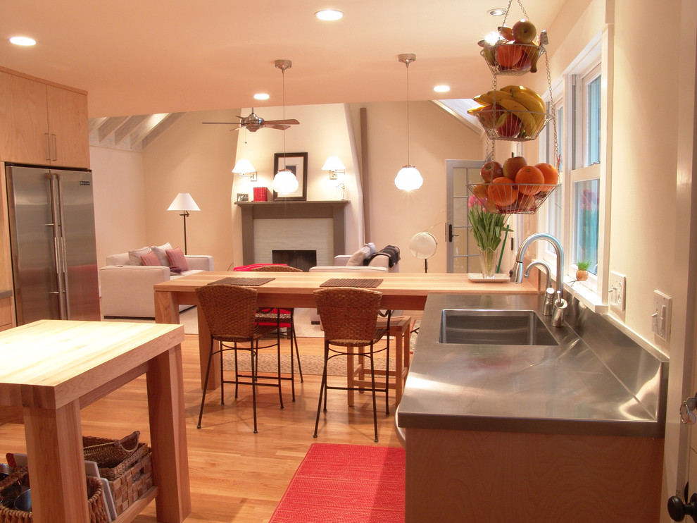 Immagine di una cucina ad ambiente unico design con lavello integrato, ante lisce, ante in legno scuro, top in acciaio inossidabile e elettrodomestici in acciaio inossidabile