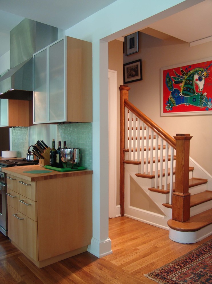 Immagine di una cucina design con ante di vetro, ante in legno scuro, paraspruzzi verde, paraspruzzi con piastrelle a mosaico, elettrodomestici in acciaio inossidabile e top in legno