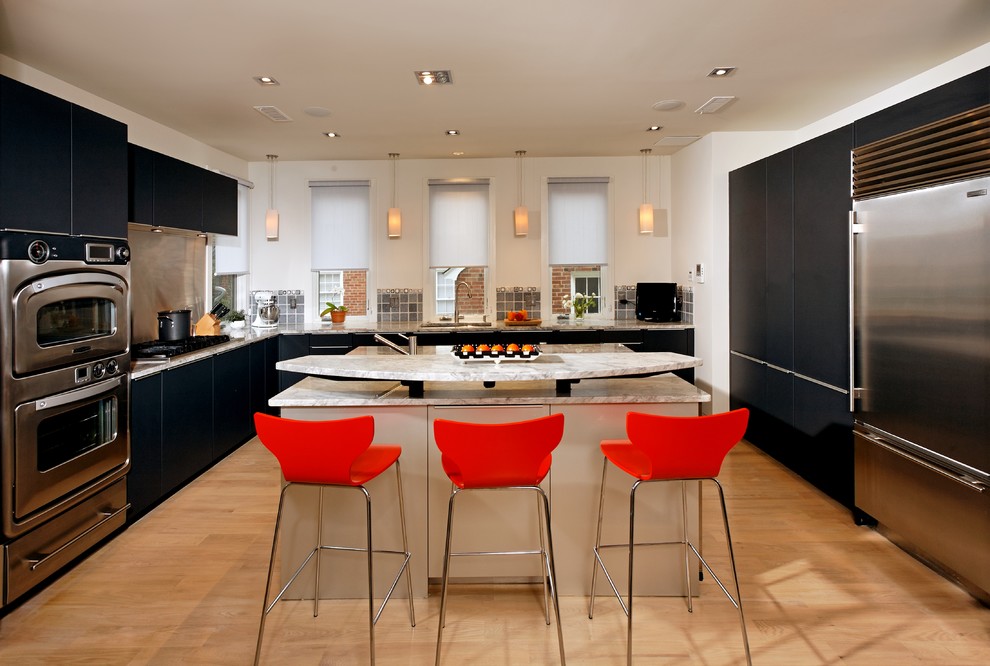 This is an example of a medium sized traditional l-shaped kitchen/diner in DC Metro with granite worktops, stainless steel appliances, flat-panel cabinets, black cabinets, a single-bowl sink, metallic splashback, metal splashback, light hardwood flooring, an island and beige floors.