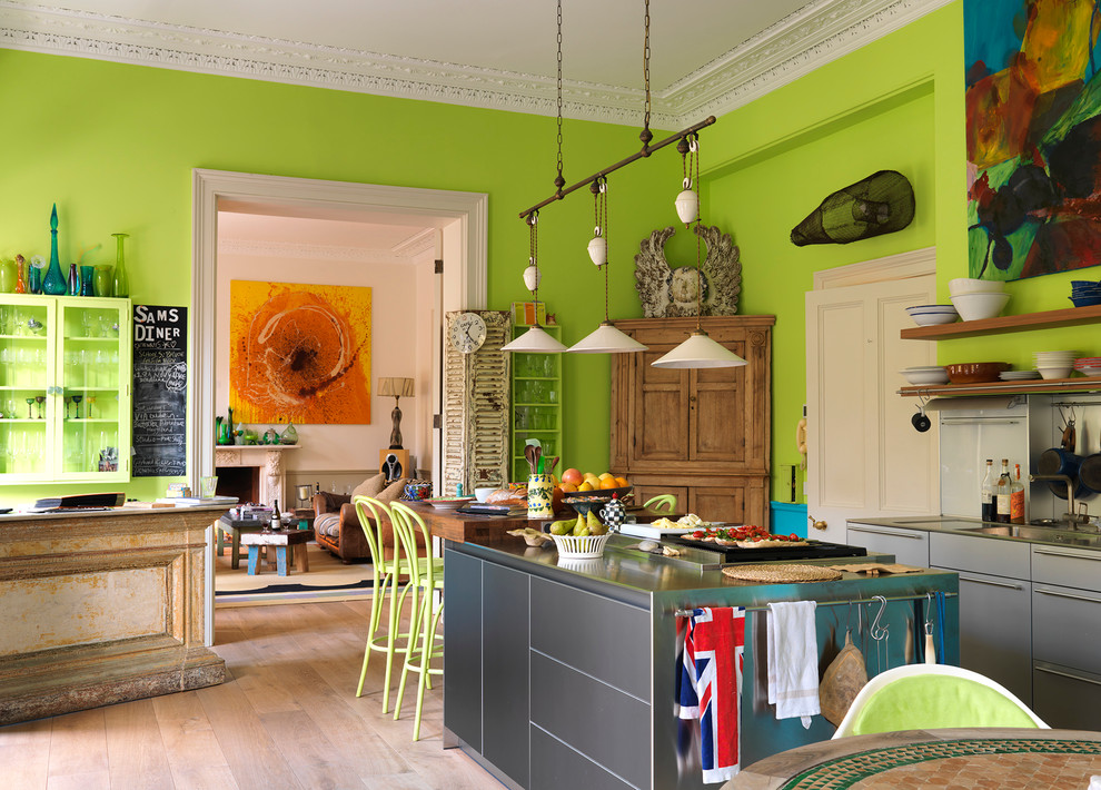 Eklektische Küche mit integriertem Waschbecken, flächenbündigen Schrankfronten, grauen Schränken, Edelstahl-Arbeitsplatte, hellem Holzboden und Kücheninsel in London