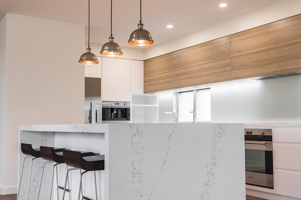 Inspiration for a large contemporary l-shaped kitchen/diner in Newcastle - Maitland with white cabinets, a submerged sink, marble worktops, white splashback, glass sheet splashback, stainless steel appliances, an island and flat-panel cabinets.