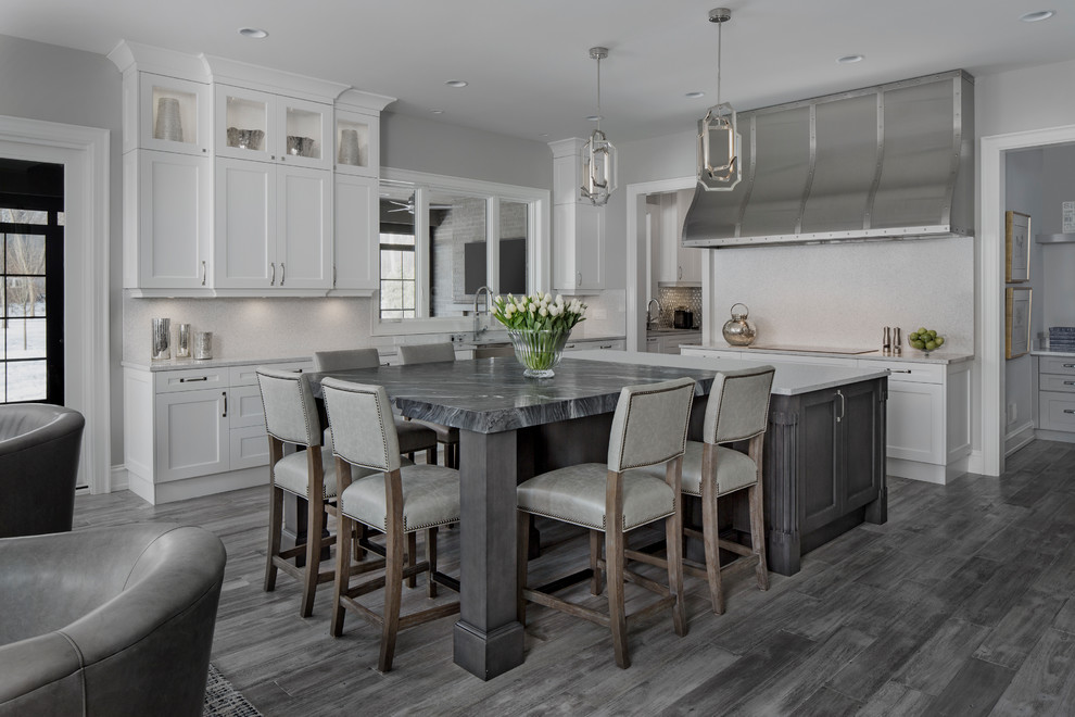 Inspiration for a large transitional u-shaped light wood floor open concept kitchen remodel in Detroit with a farmhouse sink, recessed-panel cabinets, gray cabinets, white backsplash, paneled appliances, an island and quartzite countertops