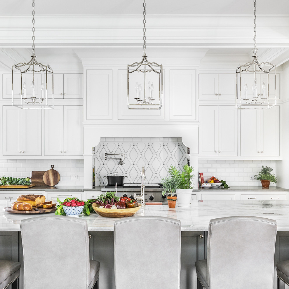 Large classic kitchen/diner in Chicago with a belfast sink, beaded cabinets, white cabinets, white splashback, ceramic splashback, stainless steel appliances, medium hardwood flooring, an island and brown floors.