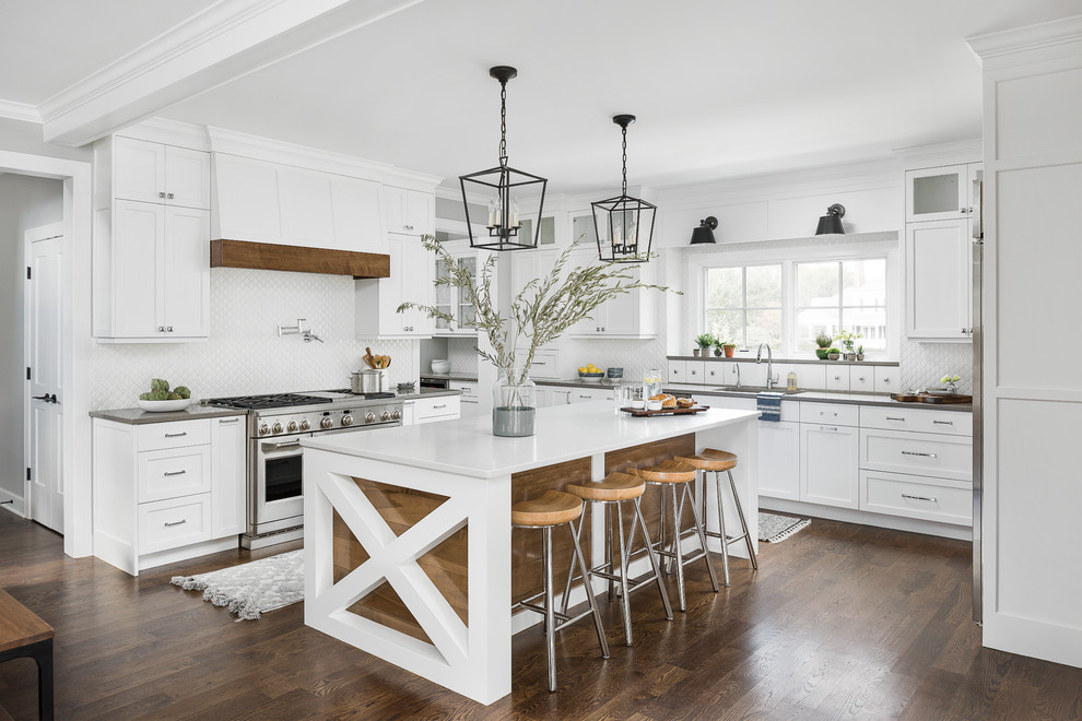 Ejemplo de cocina costera grande con fregadero bajoencimera, puertas de armario blancas, encimera de cuarzo compacto, salpicadero blanco, salpicadero de azulejos de cerámica, electrodomésticos de acero inoxidable, una isla, suelo marrón, armarios estilo shaker, suelo de madera oscura y encimeras grises