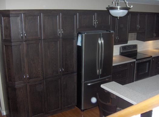 Modelo de cocina clásica renovada con armarios con paneles lisos, puertas de armario de madera oscura, encimera de acrílico y península