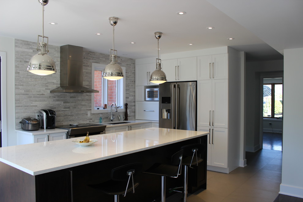 Modern inredning av ett stort grå grått kök, med en undermonterad diskho, skåp i shakerstil, vita skåp, bänkskiva i kvartsit, grått stänkskydd, stänkskydd i stickkakel, rostfria vitvaror, klinkergolv i porslin, en köksö och beiget golv