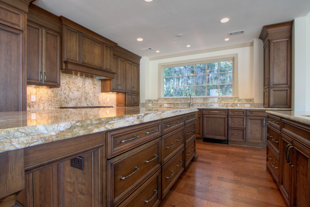 Inspiration for a huge timeless medium tone wood floor open concept kitchen remodel in Atlanta with an undermount sink, flat-panel cabinets, medium tone wood cabinets, granite countertops, stone tile backsplash, paneled appliances and two islands