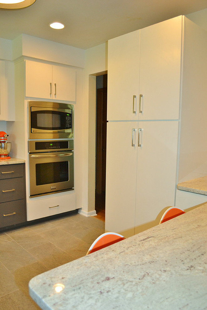 Inredning av ett modernt avskilt, mellanstort u-kök, med en undermonterad diskho, luckor med glaspanel, vita skåp, granitbänkskiva, rostfria vitvaror och en halv köksö