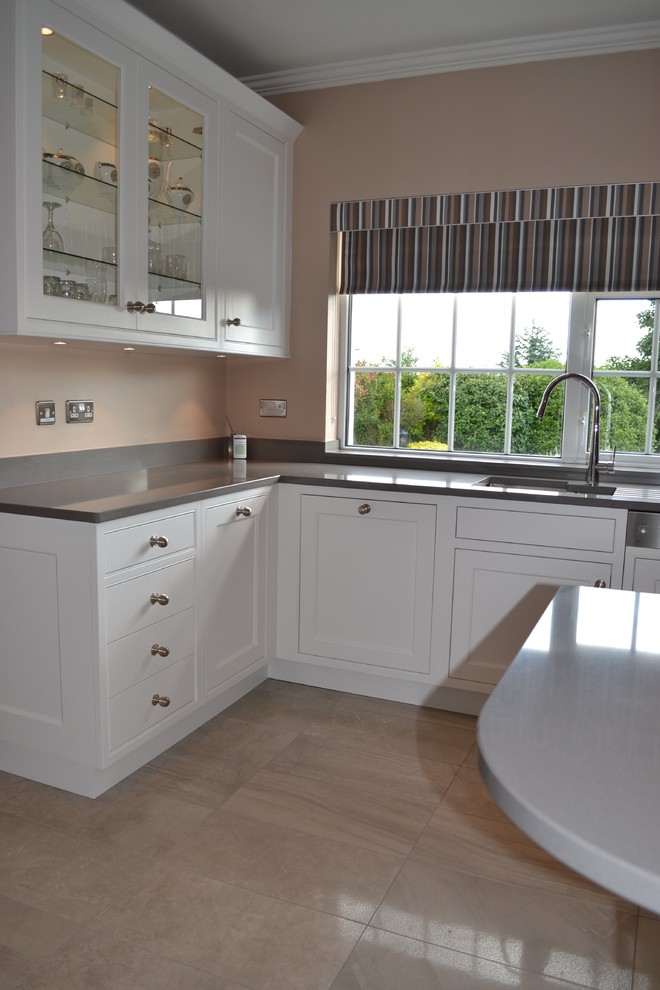 This is an example of a medium sized contemporary u-shaped kitchen/diner in Dublin with a submerged sink, beaded cabinets, white cabinets, engineered stone countertops, grey splashback, stainless steel appliances, porcelain flooring and a breakfast bar.