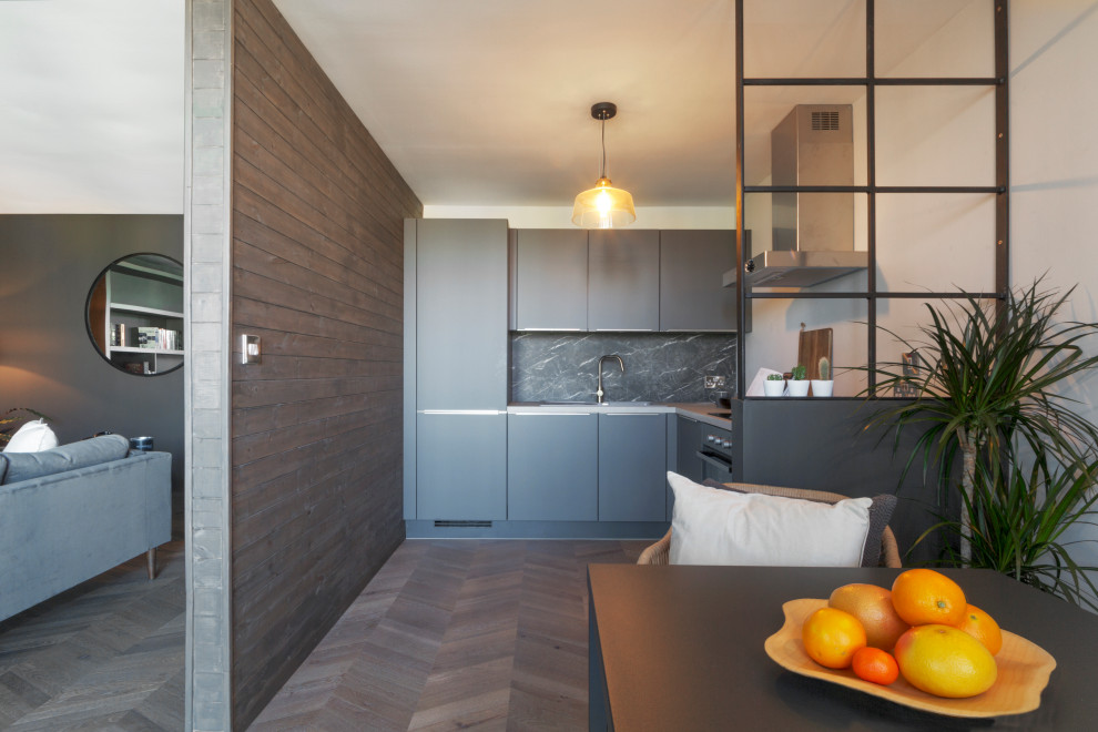 This is an example of a medium sized contemporary l-shaped open plan kitchen in Dublin with a built-in sink, flat-panel cabinets, grey cabinets, concrete worktops, black splashback, marble splashback, integrated appliances, dark hardwood flooring, no island, brown floors and grey worktops.