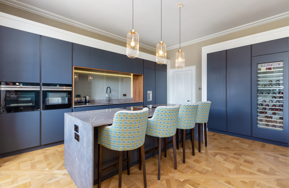 Foto di una cucina design con lavello sottopiano, ante lisce, ante blu, pavimento in legno massello medio, pavimento marrone e top grigio