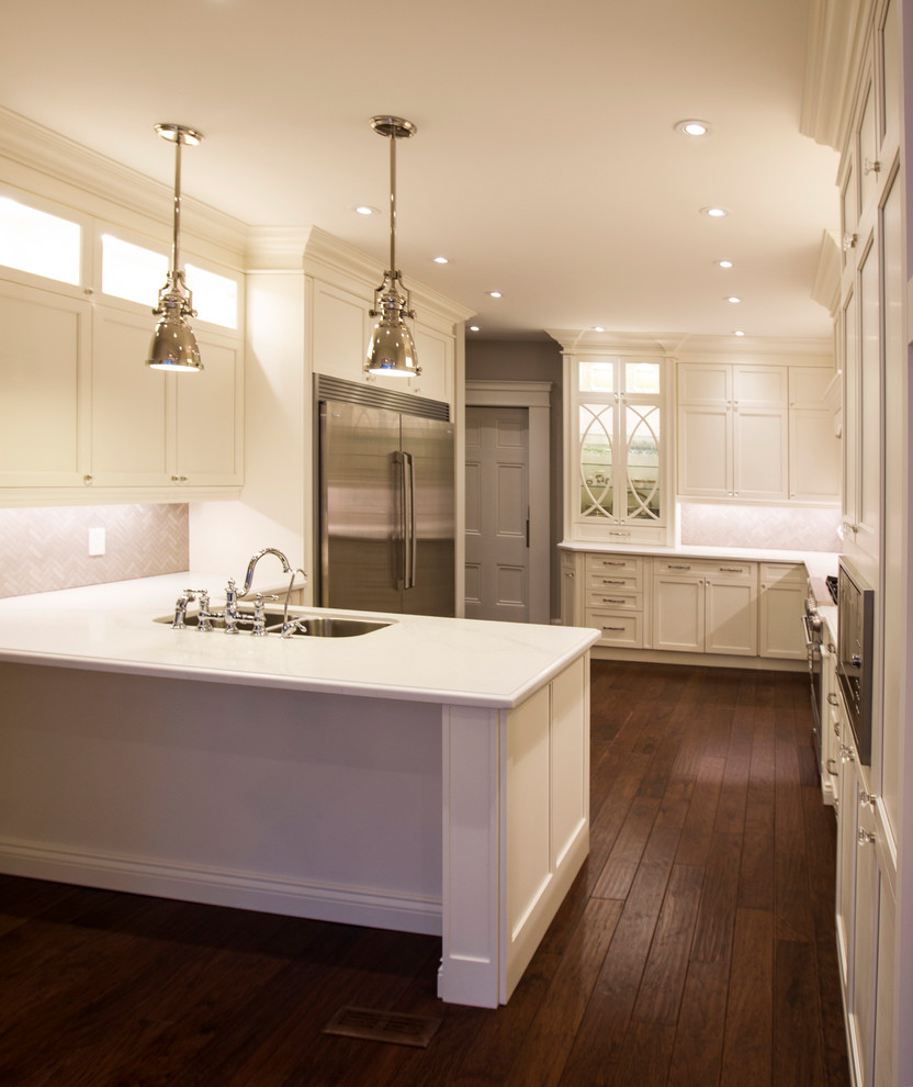 Example of a large transitional l-shaped dark wood floor and brown floor enclosed kitchen design in Toronto with an undermount sink, white cabinets, quartz countertops, gray backsplash, mosaic tile backsplash, a peninsula and shaker cabinets