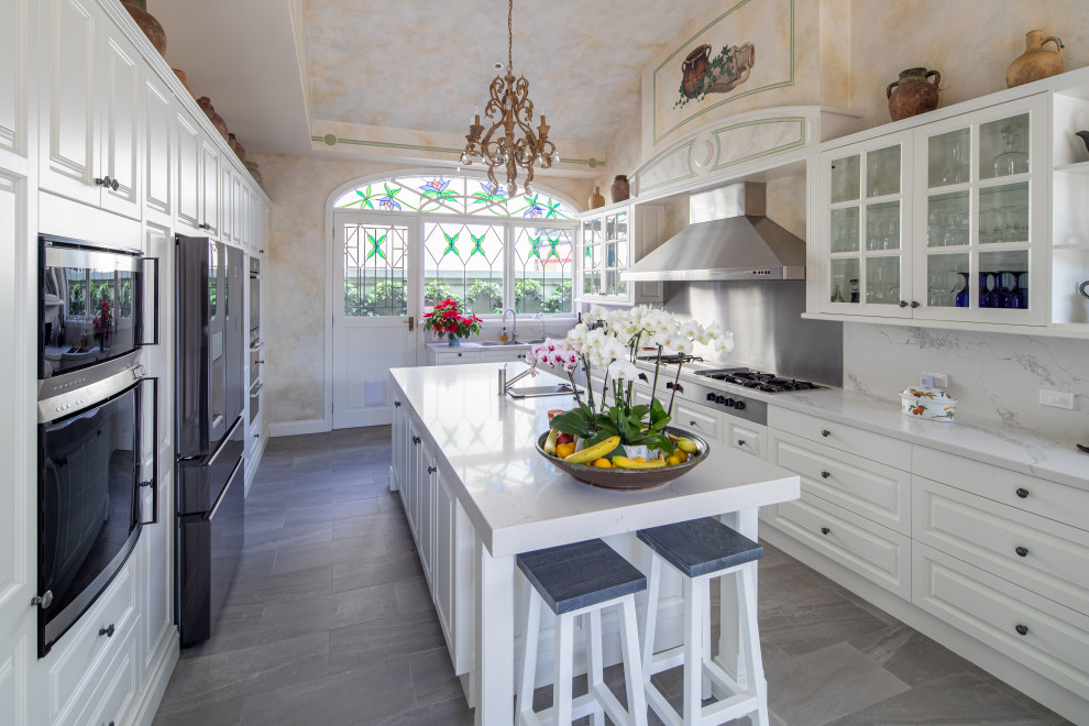 Zweizeilige Klassische Küche mit profilierten Schrankfronten, weißen Schränken, Küchenrückwand in Weiß, Küchengeräten aus Edelstahl, Kücheninsel, grauem Boden und weißer Arbeitsplatte in Sydney