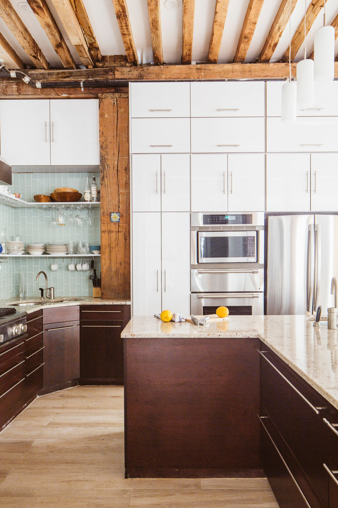 Example of a mid-sized urban u-shaped light wood floor eat-in kitchen design in New York with a single-bowl sink, flat-panel cabinets, white cabinets, granite countertops, gray backsplash, glass tile backsplash, stainless steel appliances and an island