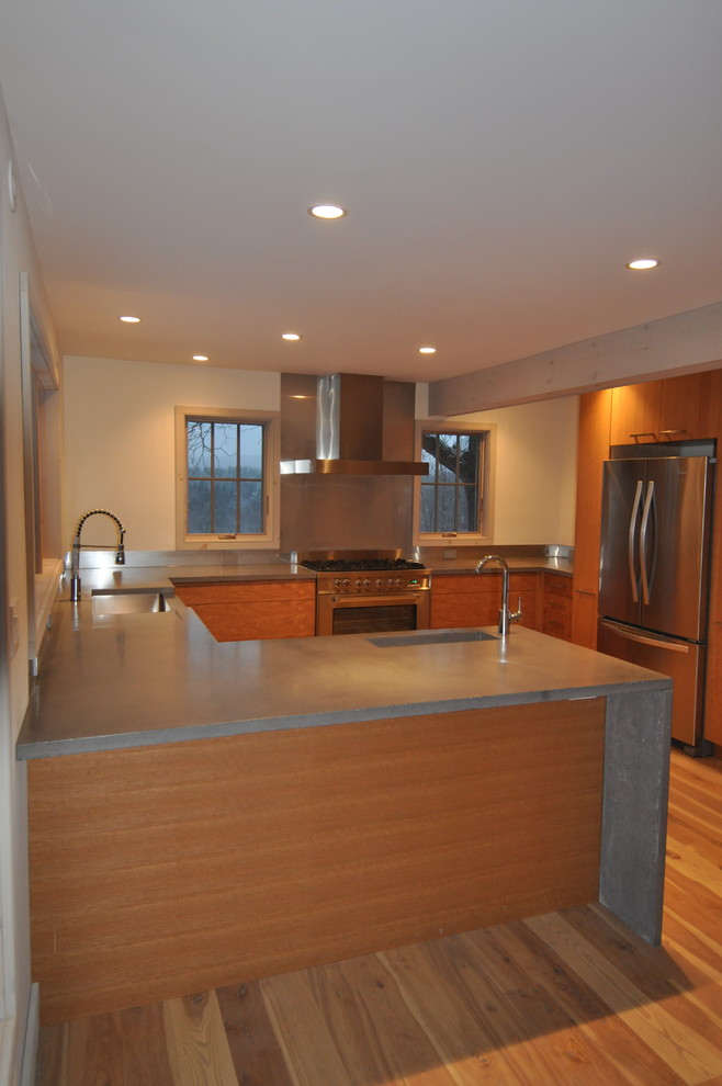 This is an example of a large traditional l-shaped open plan kitchen in Boston with a belfast sink, flat-panel cabinets, dark wood cabinets, stainless steel worktops, stainless steel appliances, light hardwood flooring, no island and beige floors.