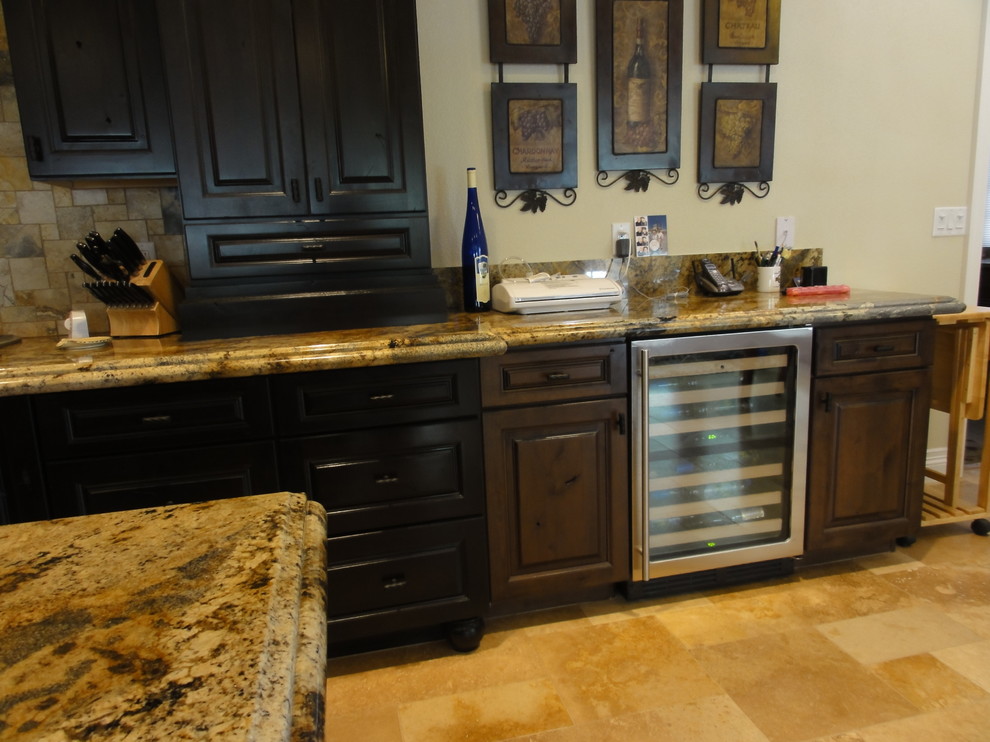 Exempel på ett medelhavsstil kök, med en undermonterad diskho, luckor med upphöjd panel, skåp i mörkt trä, granitbänkskiva, beige stänkskydd, stänkskydd i stenkakel och rostfria vitvaror