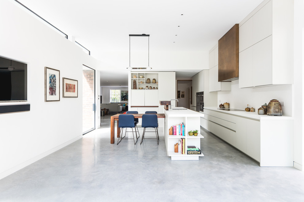 Immagine di un grande cucina con isola centrale design con ante lisce, ante bianche, elettrodomestici colorati, pavimento in cemento, pavimento grigio e top bianco