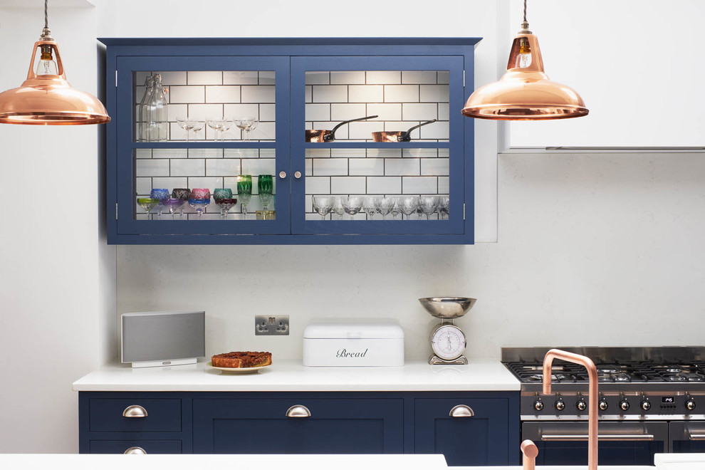 Inspiration for a large contemporary single-wall kitchen/diner in London with a double-bowl sink, shaker cabinets, blue cabinets, quartz worktops, white splashback, stone slab splashback, stainless steel appliances, dark hardwood flooring, an island and brown floors.