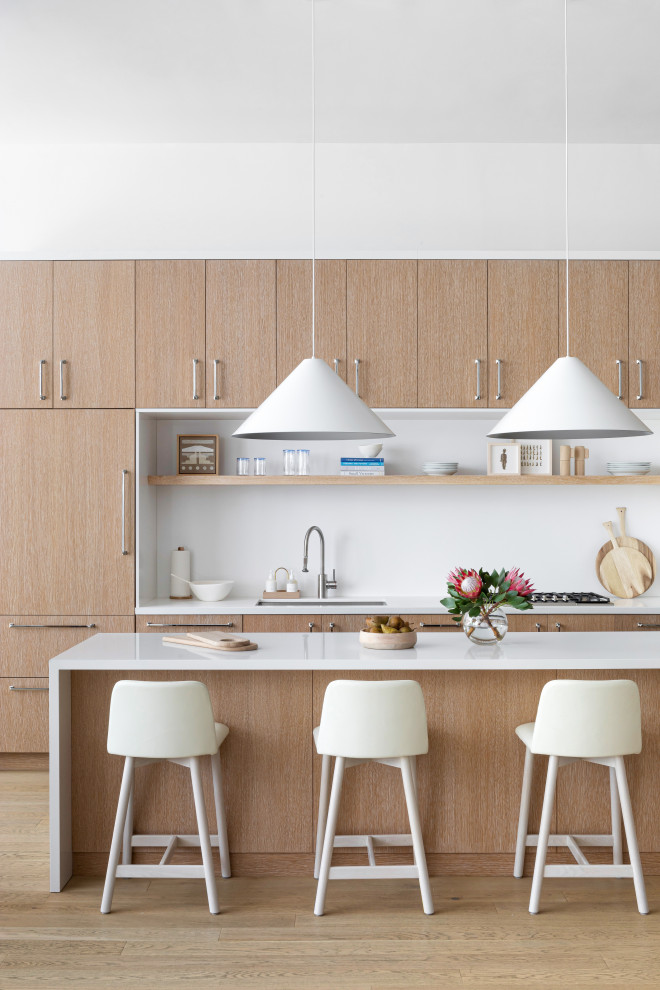 Photo of a large contemporary u-shaped kitchen/diner in New York with a built-in sink, flat-panel cabinets, light wood cabinets, wood worktops, white splashback, marble splashback, stainless steel appliances, light hardwood flooring, an island, brown floors and white worktops.