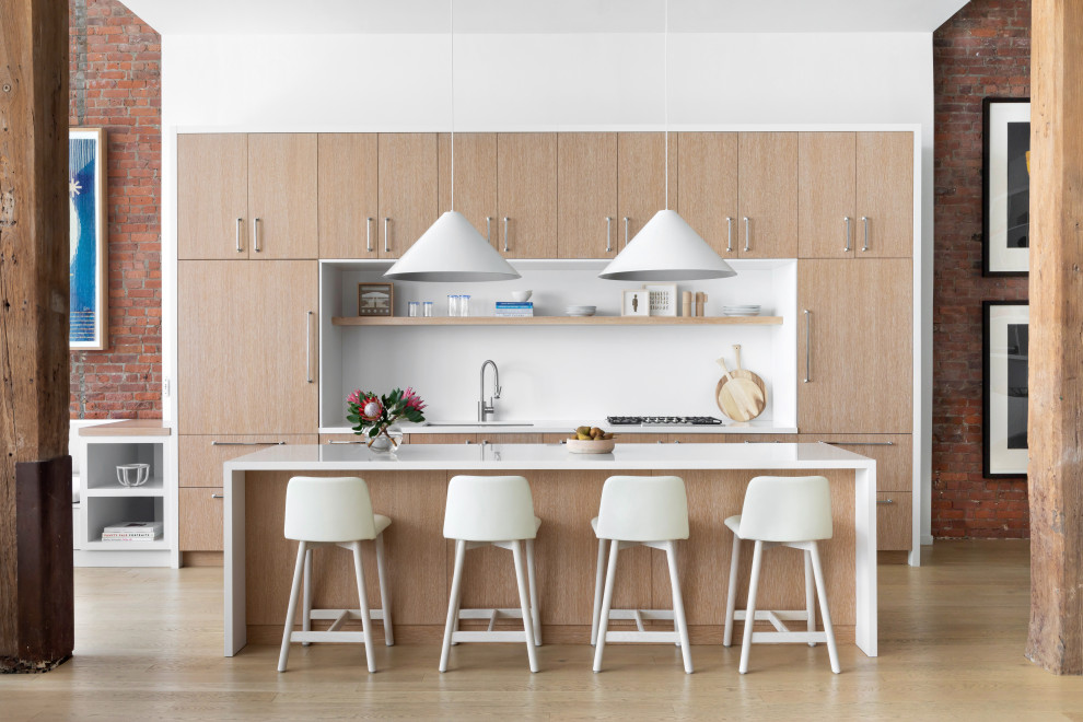Inspiration for a large contemporary u-shaped kitchen/diner in New York with a built-in sink, flat-panel cabinets, light wood cabinets, wood worktops, white splashback, marble splashback, stainless steel appliances, light hardwood flooring, an island, brown floors and white worktops.