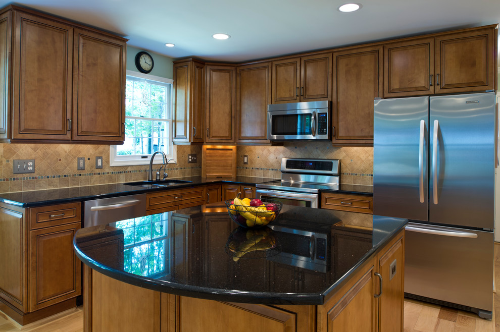 Inspiration for a mid-sized timeless l-shaped light wood floor open concept kitchen remodel in DC Metro with an undermount sink, raised-panel cabinets, medium tone wood cabinets, granite countertops, beige backsplash, stone tile backsplash, stainless steel appliances and an island
