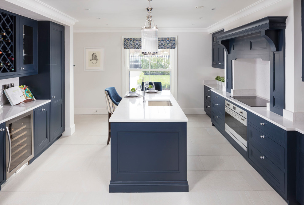 Klassische Küche in U-Form mit Schrankfronten im Shaker-Stil, blauen Schränken, Quarzit-Arbeitsplatte, Rückwand aus Spiegelfliesen, Küchengeräten aus Edelstahl, Kücheninsel, Unterbauwaschbecken und Küchenrückwand in Weiß in Dublin