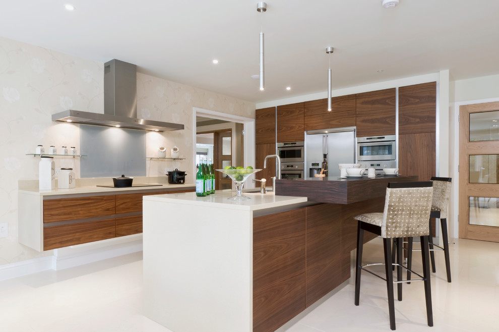 Inspiration for a medium sized contemporary kitchen in Buckinghamshire with flat-panel cabinets, grey splashback, glass sheet splashback, stainless steel appliances, an island, white floors, white worktops, a submerged sink and dark wood cabinets.