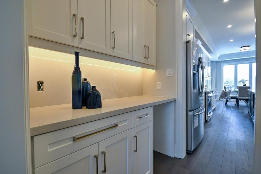 Exempel på ett mellanstort klassiskt vit vitt kök, med en undermonterad diskho, luckor med infälld panel, vita skåp, bänkskiva i kvartsit, vitt stänkskydd, rostfria vitvaror, mellanmörkt trägolv, en köksö och brunt golv