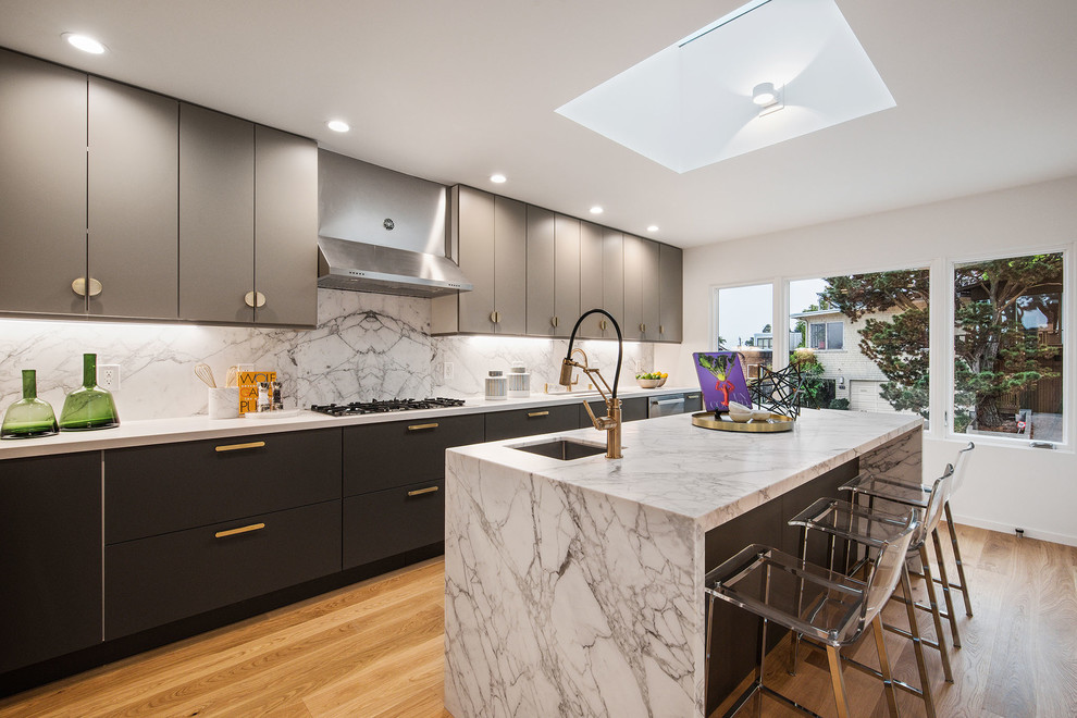 Inspiration for a mid-sized contemporary l-shaped medium tone wood floor and brown floor eat-in kitchen remodel in San Francisco with a single-bowl sink, flat-panel cabinets, gray cabinets, marble countertops, white backsplash, stone slab backsplash, stainless steel appliances, an island and white countertops